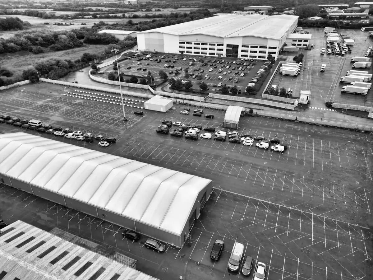 Vista aérea de complejo logístico con bodega de gran formato y tractocamiones — referencia para la Zona Franca Santander