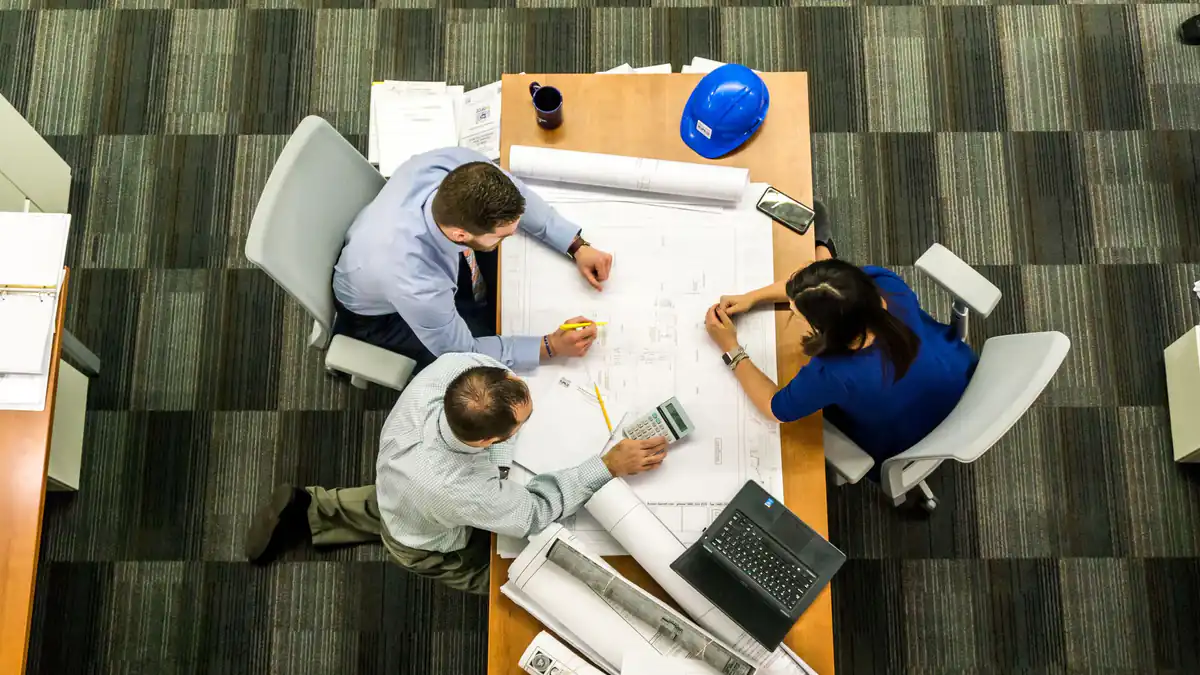 Personas revisando una mesa de trabajo antes de firmar una promesa de compraventa